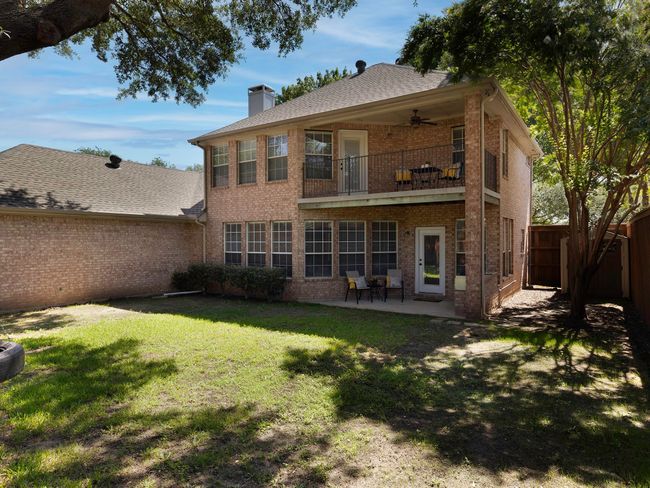 Rear view of property featuring a balcony, brick siding, ceiling fan, a chimney, and a patio | Image 32