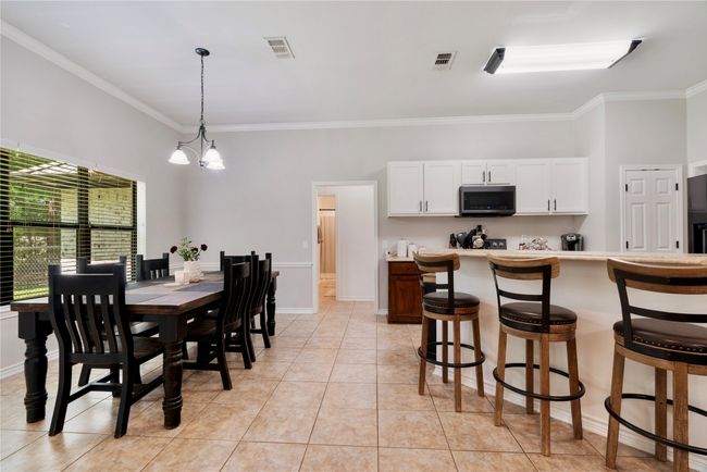 Dining area featuring ornamental molding, light tile patterned floors, baseboards, a notable chandelier, and visible vents | Image 9