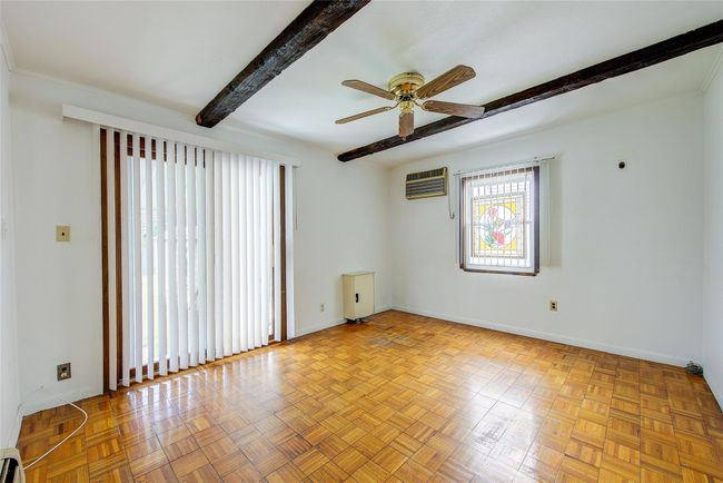 Spare room featuring beam ceiling, a wall unit AC, a ceiling fan, and a baseboard radiator | Image 16