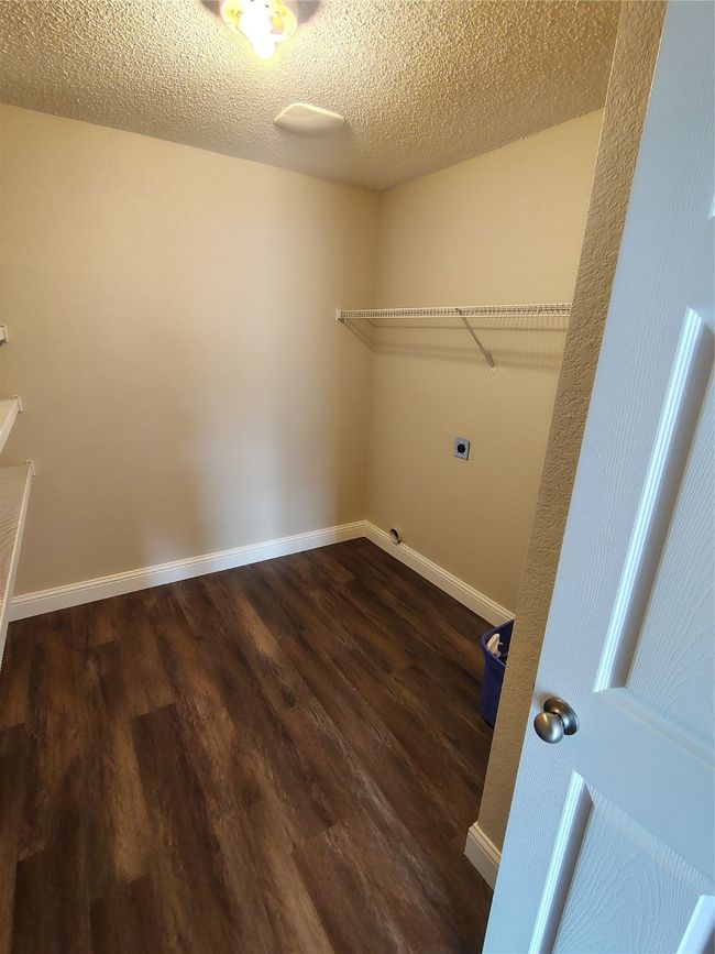 Washroom featuring electric dryer hookup, dark wood finished floors, baseboards, and a textured ceiling | Image 24