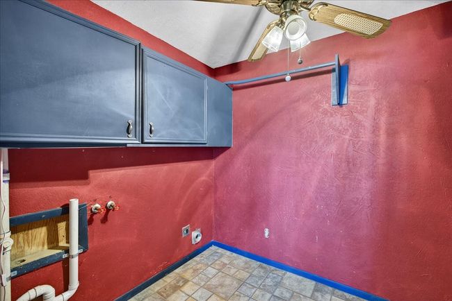 Washroom featuring hookup for an electric dryer, cabinet space, a ceiling fan, stone finish flooring, and hookup for a washing machine | Image 31