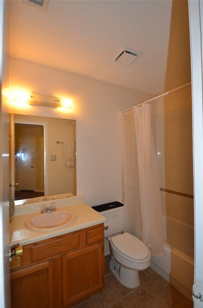Full bathroom with toilet, tile patterned floors, a textured ceiling, vanity, and shower / bath combo with shower curtain | Image 9