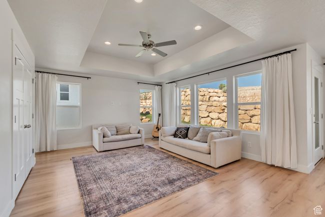 Living room with a tray ceiling, light wood-style floors, a ceiling fan, and recessed lighting | Image 13