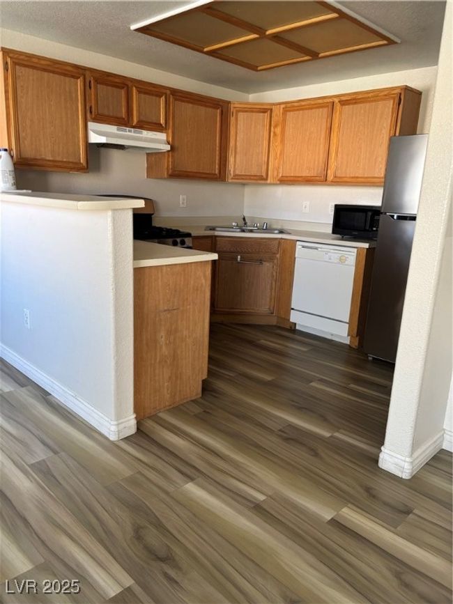 Kitchen featuring dishwasher, exhaust hood, refrigerator, dark wood-style floors, and brown cabinets | Image 7