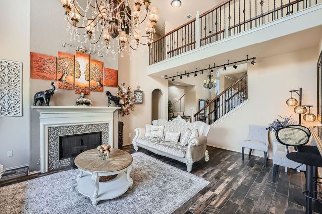 Living room featuring a towering ceiling, arched walkways, a chandelier, dark wood finished floors, and stairway | Image 8