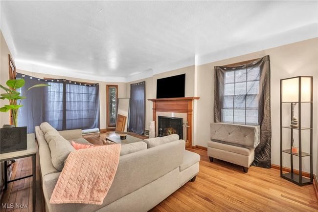Living area featuring baseboards, wood finished floors, and a fireplace with raised hearth | Image 6