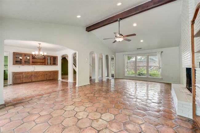 Unfurnished living room featuring a fireplace, ceiling fan, a chandelier, arched walkways, and a sink | Image 6