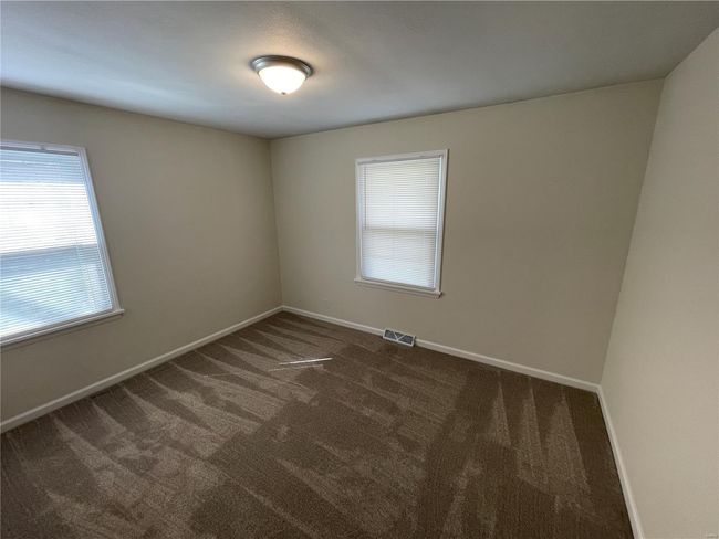 Empty room with dark carpet, a healthy amount of sunlight, and visible vents | Image 28