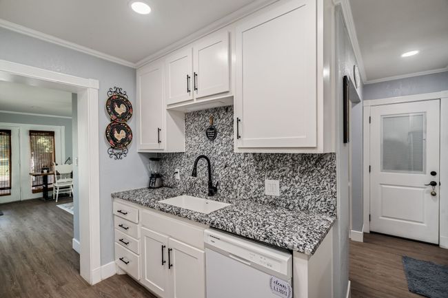 Kitchen featuring dishwasher, ornamental molding, dark wood finished floors, decorative backsplash, and light stone counters | Image 10