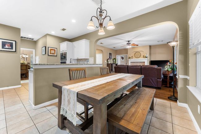 Dining room featuring arched walkways, light tile patterned floors, a ceiling fan, a chandelier, and a​​‌​​​​‌​​‌‌​‌‌​​​‌‌​​‌‌​‌​​​​​‌ fireplace | Image 9
