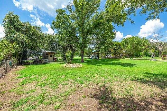View of yard featuring a trampoline, a playground, and a shed | Image 36