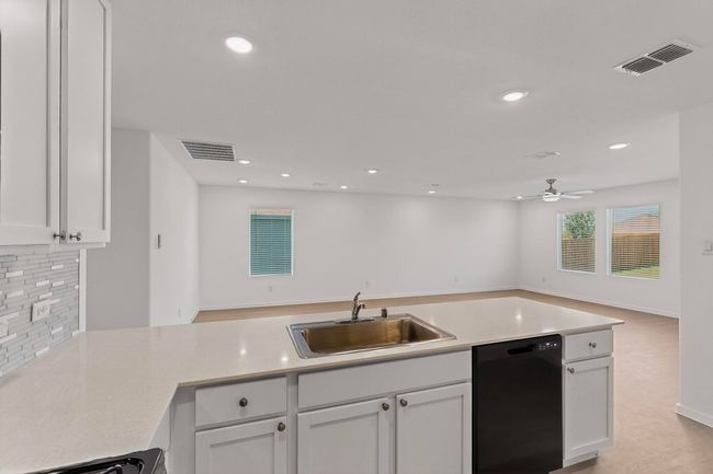 Kitchen featuring dishwasher, a sink, open floor plan, backsplash, and ceiling fan | Image 11