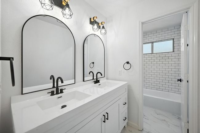 Bathroom with double vanity, marble finish floors, and bathing tub / shower combination | Image 17