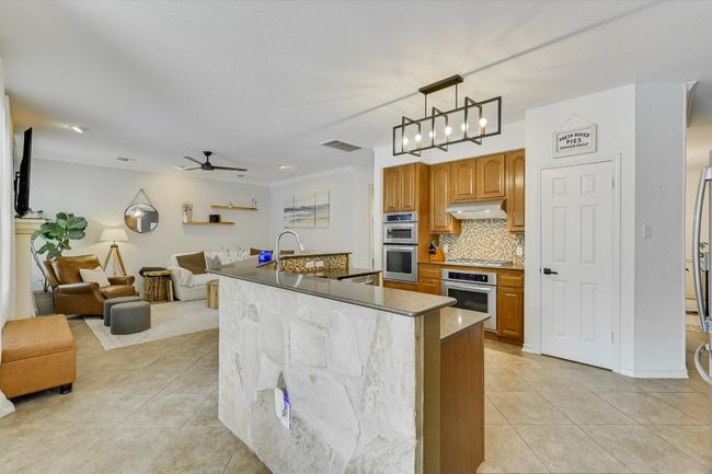 Kitchen featuring extractor fan, light tile patterned flooring, stainless steel appliances, and open floor plan | Image 9
