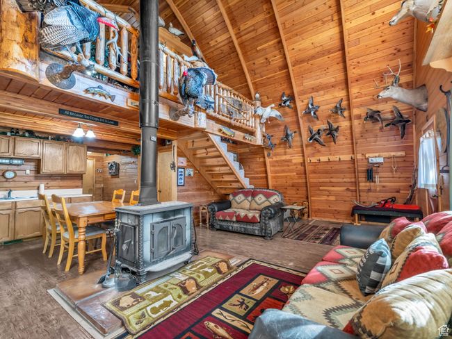 Living area featuring wooden walls, a wood ceiling with exposed beams, a wood stove, wood finished floors, and high vaulted ceiling | Image 7