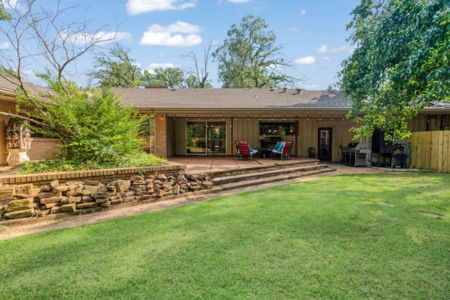 Rear view of house with board and batten siding, a shingled roof, a lawn, brick siding, and a patio area | Image 26