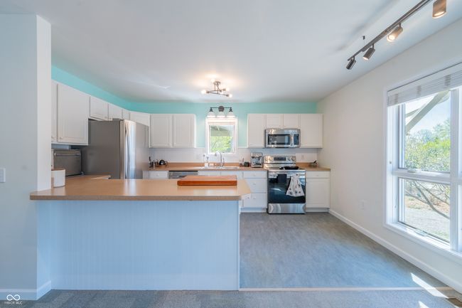 kitchen featuring stainless steel appliances, a peninsula, baseboards, and white cabinetry | Image 7