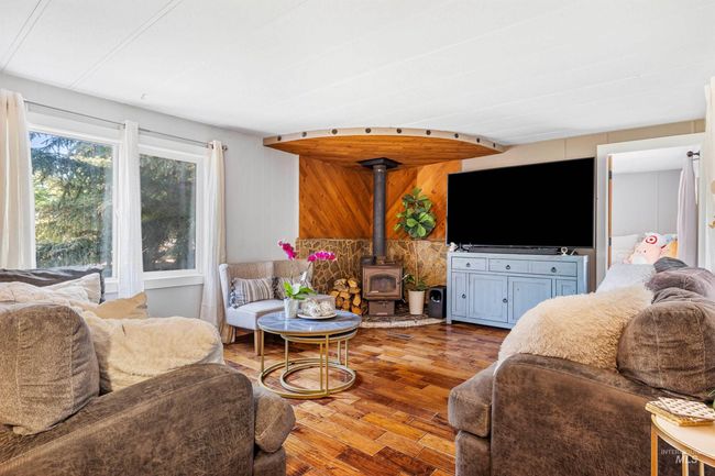 Living area featuring wood finished floors and a wood stove | Image 4