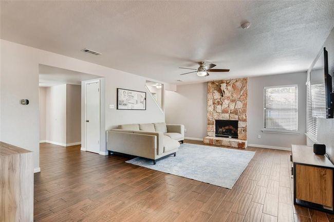 Living area with ceiling fan, dark wood-style floors, a stone fireplace, baseboards, and a textured ceiling | Image 6