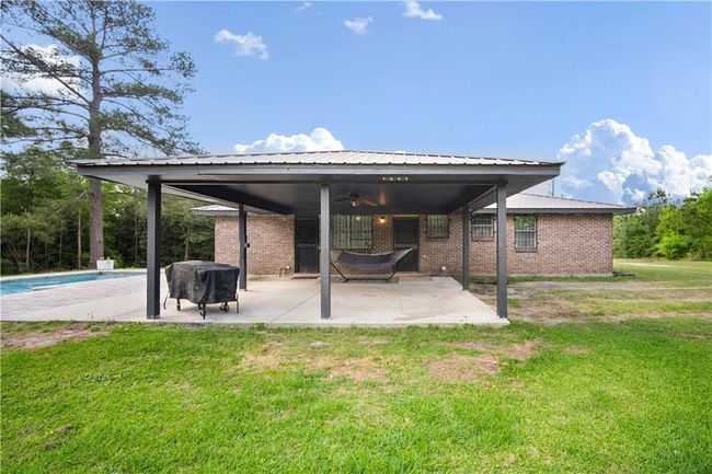 Rear view of house with a ceiling fan, an outdoor pool, a patio area, brick siding, and a yard | Image 19