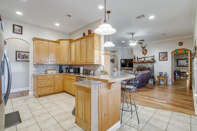 Kitchen featuring a breakfast bar, light brown cabinets, a peninsula, open floor plan, and ceiling fan | Image 6