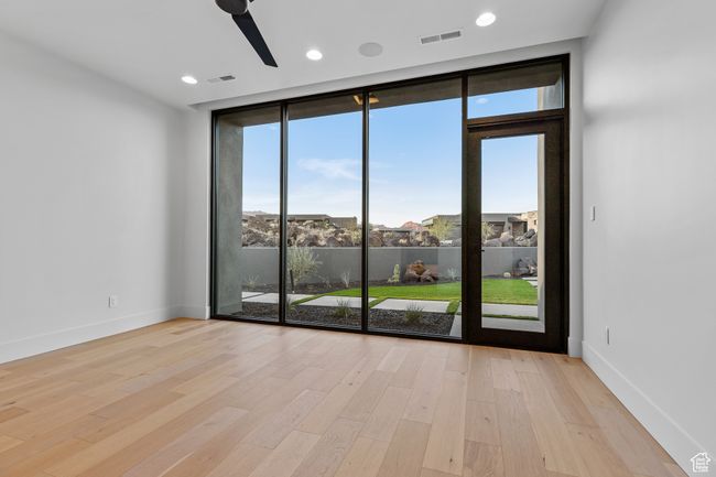 Unfurnished room with ceiling fan, light wood-style floors, visible vents, and a wall of windows | Image 23