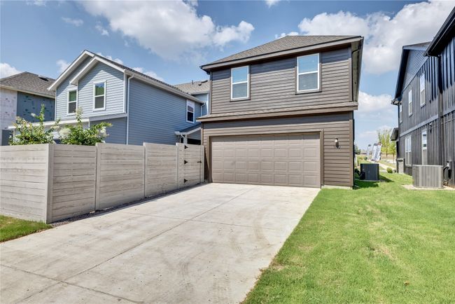 View of front facade with an attached garage, central AC, fence, concrete driveway, and a front yard | Image 28