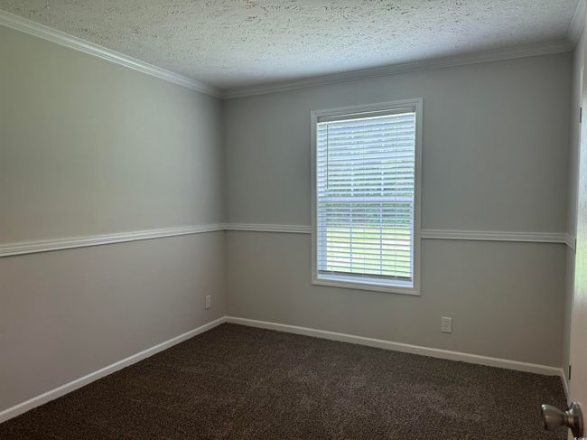 Spare room featuring plenty of natural light, a textured ceiling, dark carpet, and crown molding | Image 27
