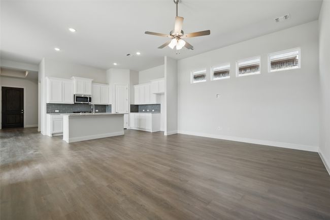 Unfurnished living room with visible vents, a ceiling fan, baseboards, and dark wood-style flooring | Image 15