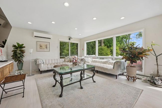 Living area with a wall mounted AC, recessed lighting, light wood-style floors, and a baseboard radiator | Image 14