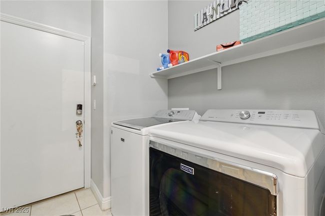 Clothes washing area featuring light tile patterned floors, washer and dryer, and laundry area | Image 33