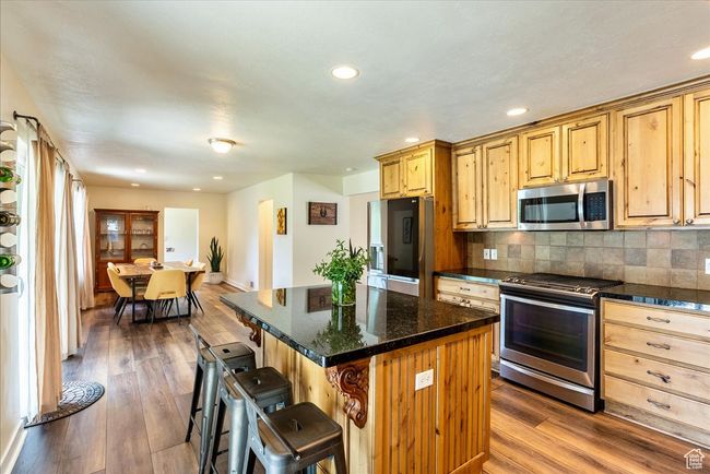 Kitchen with stainless steel appliances, a kitchen breakfast bar, dark wood-type flooring, a center island, and recessed lighting | Image 21