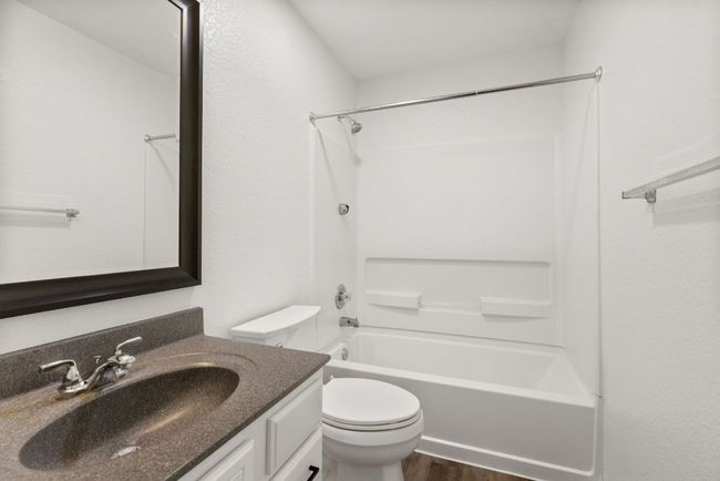 Full bath featuring Grey wood-style vinyl floors, vanity, toilet, and shower / washtub combination | Image 29