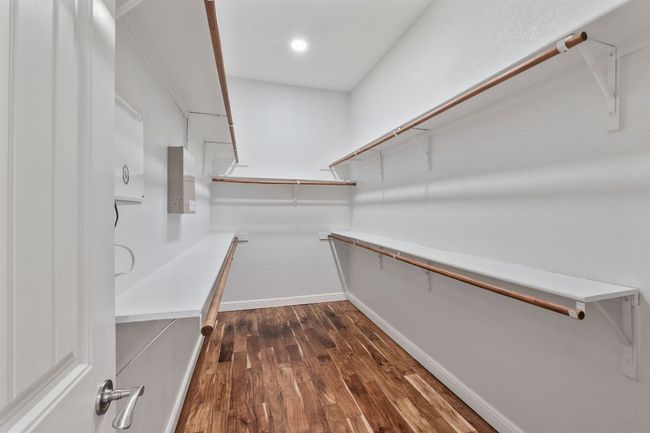 Master bedroom closet is large with built-ins, and hardwood flooring. | Image 12