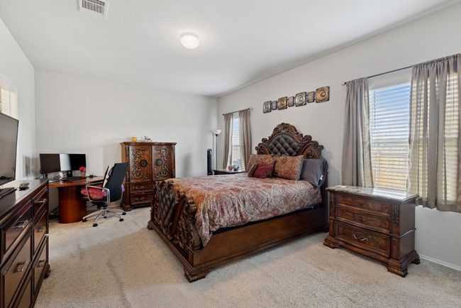 Bedroom featuring light carpet, multiple windows, and an office area | Image 27