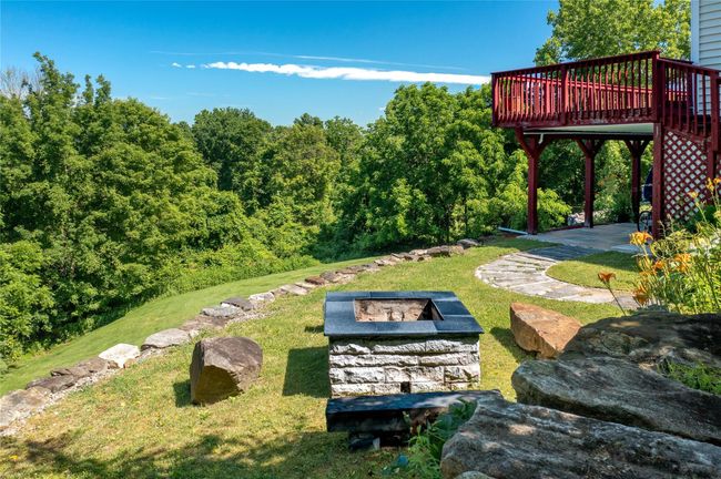 View of green lawn featuring a wooden deck and a fire pit | Image 6