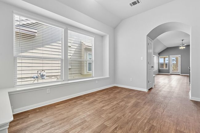 Front Dining area or bonus area with vaulted ceiling, arched walkways, light wood-style flooring, and a ceiling fan | Image 5