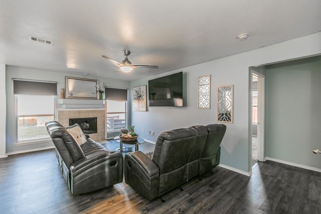 Living area featuring dark wood finished floors, ceiling fan, and a tile fireplace | Image 13