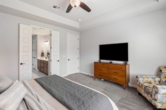 Bedroom with light colored carpet, connected bathroom, and a ceiling fan | Image 16