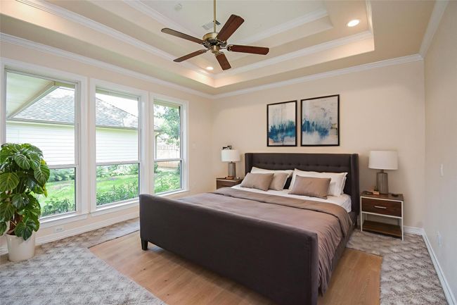This spacious room features large windows providing ample natural light, a decorative tray ceiling with recessed lighting, a ceiling fan, and patterned carpet flooring. Ideal for a bright and comfortable living space. *Virtually staged | Image 28