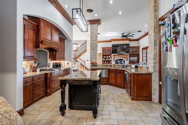 Kitchen featuring pendant lighting, a kitchen bar, light stone counters, and appliances with stainless steel finishes | Image 15