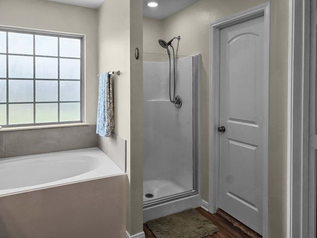 Bathroom with a stall shower, a garden tub, and wood finished floors | Image 20
