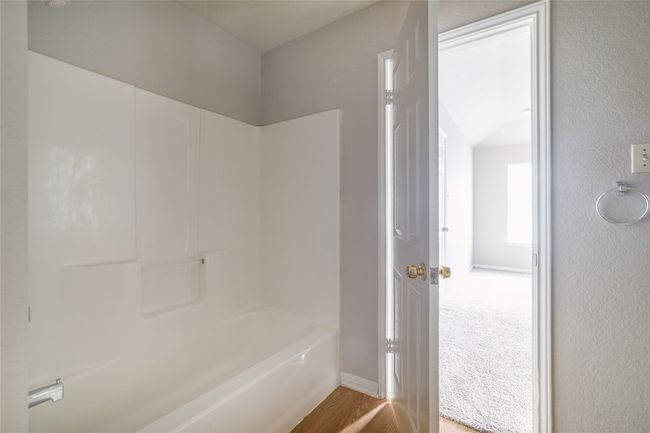 Bathroom with wood finished floors, shower / tub combination, and baseboards | Image 14