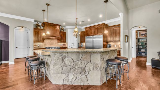 Kitchen with stainless steel built in fridge, custom exhaust hood, a kitchen bar, arched walkways, and crown molding | Image 14