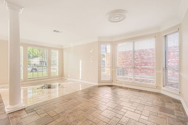 Unfurnished room with ornate columns, stone finish floor, ornamental molding, visible vents, and baseboards | Image 14