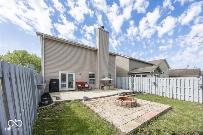 rear view of house featuring a fire pit, a lawn, a chimney, and a patio | Image 26