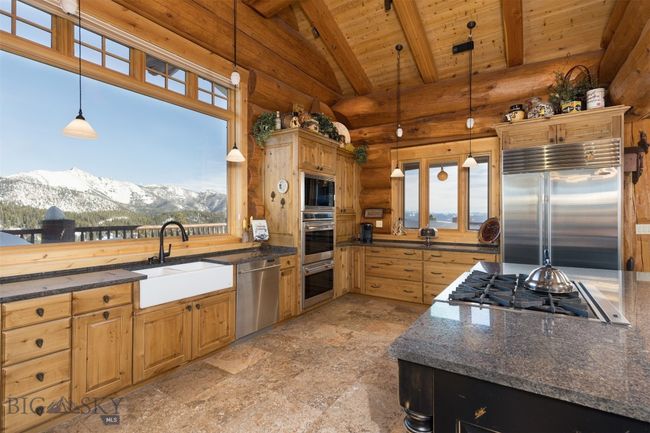 Main level kitchen with pendant lighting, stunning mountain views, double farmhouse sink and built-in stainless steel appliances. | Image 31