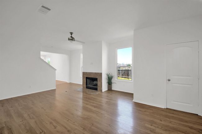 Unfurnished living room featuring baseboards, visible vents, a tile fireplace, ceiling fan, and wood finished floors | Image 6