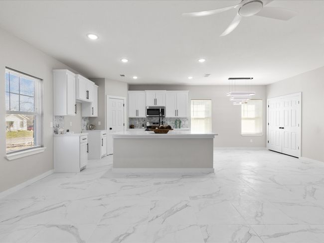 Kitchen with stainless steel microwave, tasteful backsplash, a healthy amount of sunlight, and white cabinets | Image 9