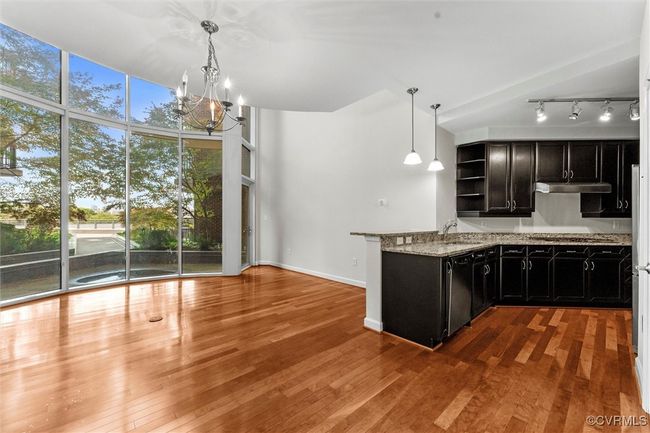 Kitchen with dark cabinetry, dishwasher, open shelves, track lighting, and under cabinet range hood | Image 7